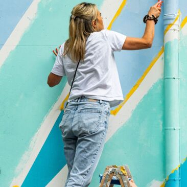 Schülerinnen streichen eine Wand für eine Schulhofgestaltung gegen Vandalismus mit Handwerksförderung in Konstanz