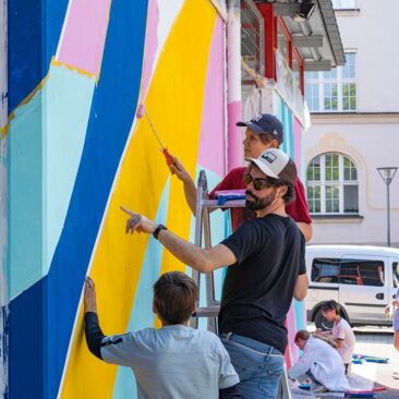 Schülerinnen streichen eine Wand für eine Schulhofgestaltung gegen Vandalismus mit Handwerksförderung in Konstanz