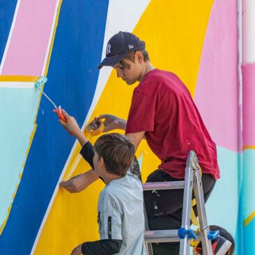 Schülerinnen streichen eine Wand für eine Schulhofgestaltung gegen Vandalismus mit Handwerksförderung in Konstanz